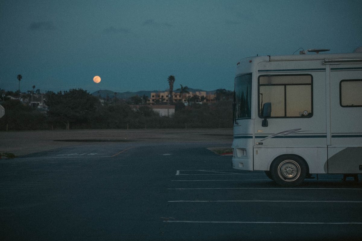Camper parked under palm trees in the evening with the moon rising
